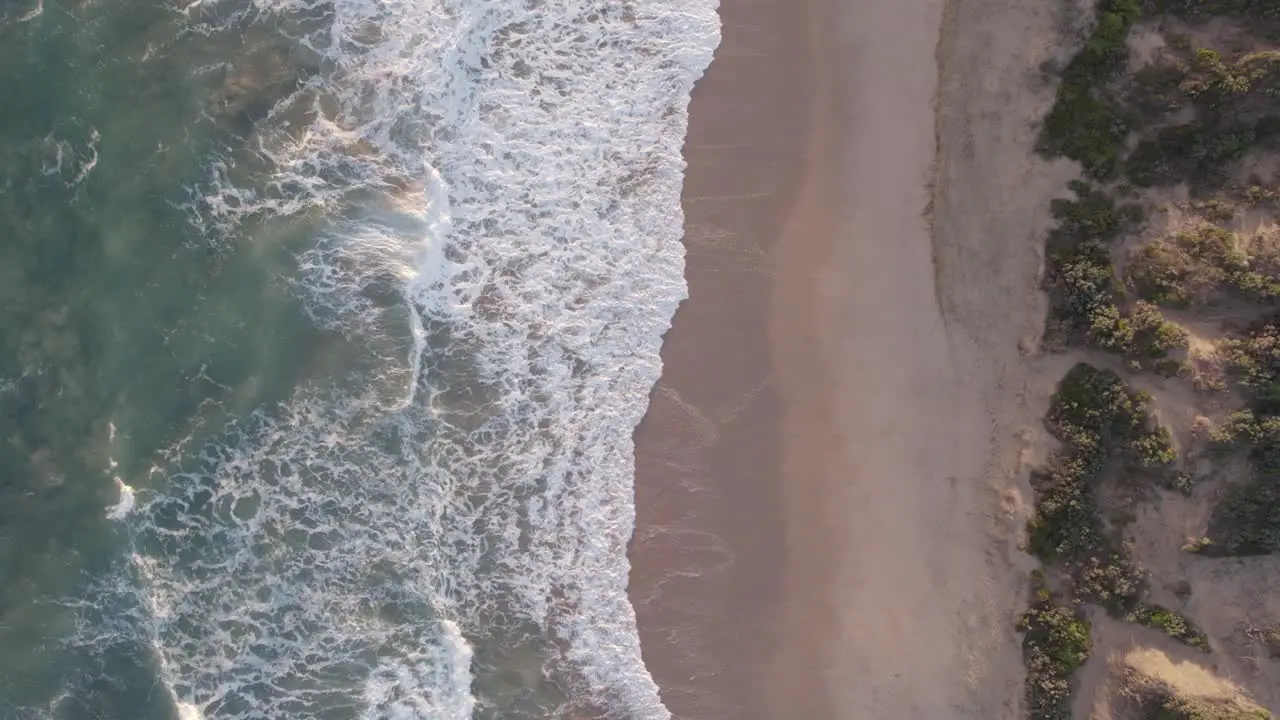 Vertical slow moving drone footage of waves hitting the beach at Point Lonsdale Victoria Australia