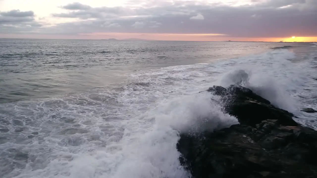 Tide rolling in at sunset crashing on rocks