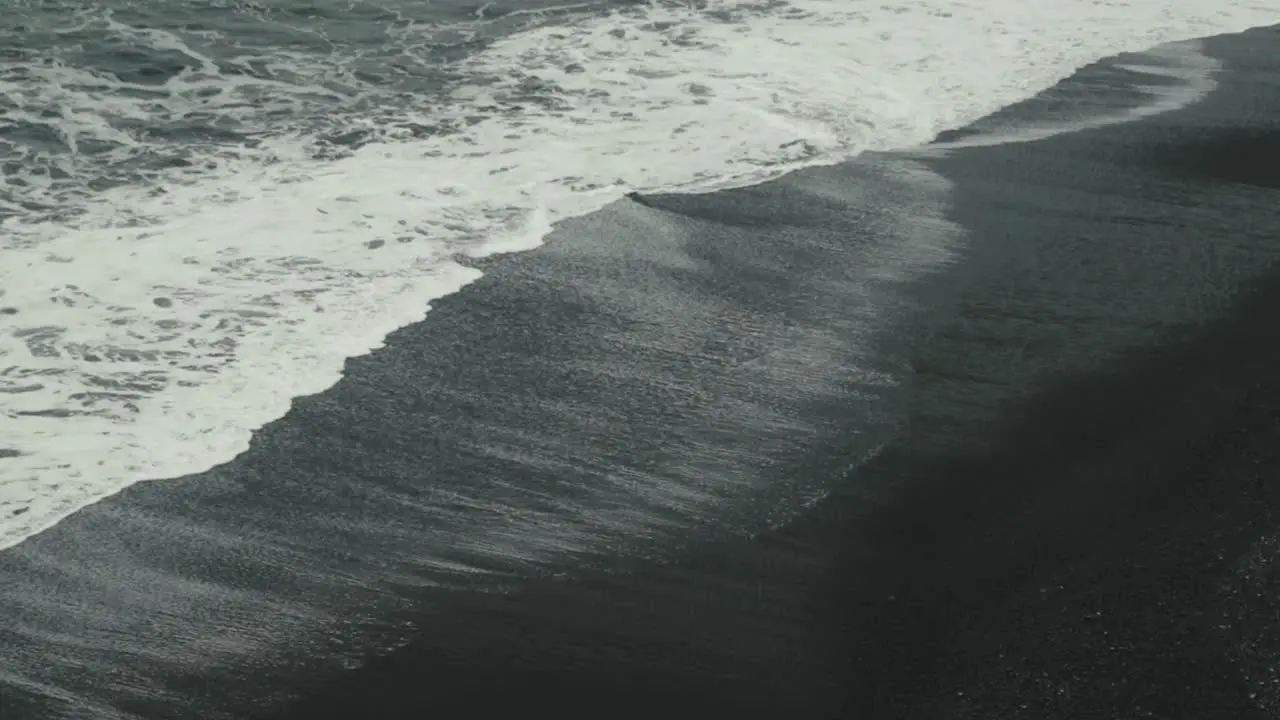 Aerial of waves crashing on a black sand beach in Iceland