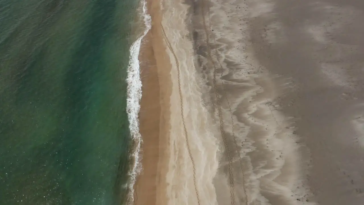 Abstract scenery of waves giving natural shapes to sand beach in Iceland aerial