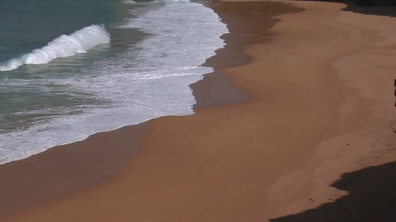 Blue Green Waves Wash Onto A Sandy Beach