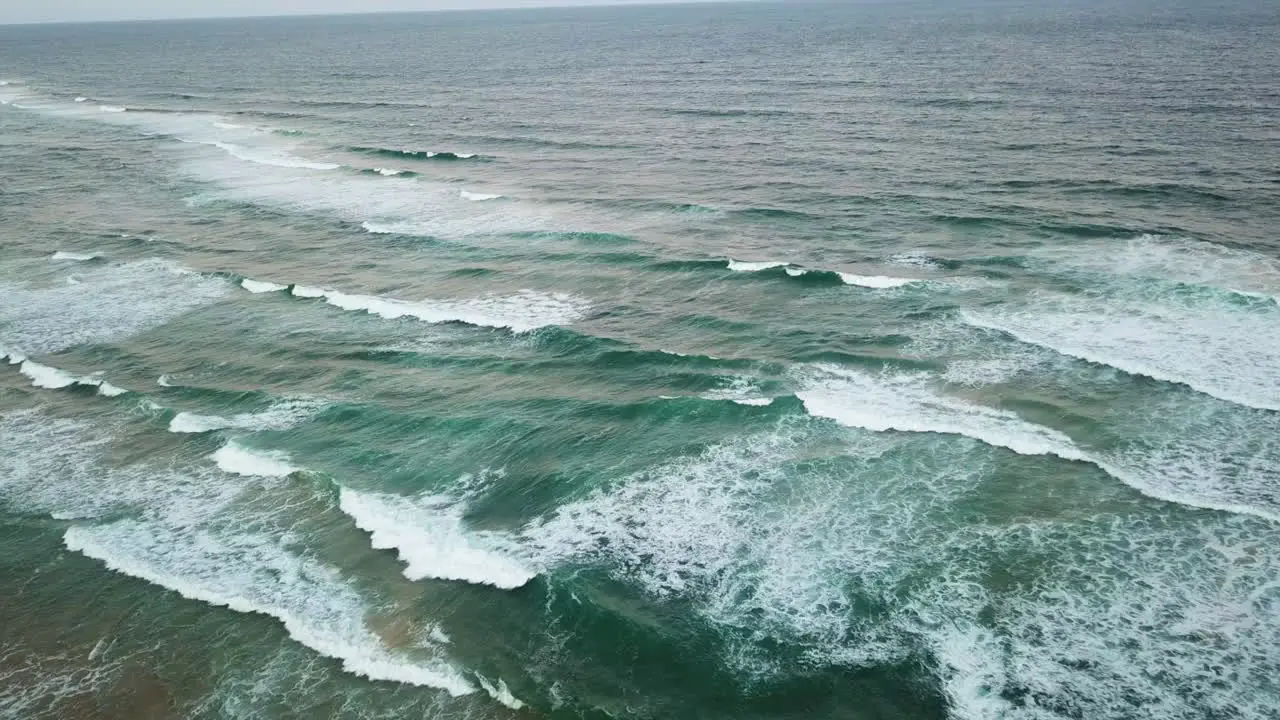 drone shot slowly dropping towards breaking waves