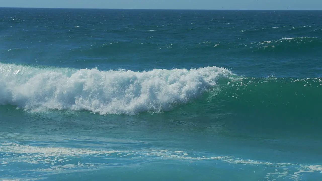 Close-up slow motion shot of sea waves breaking on sandy coastline in Portugal