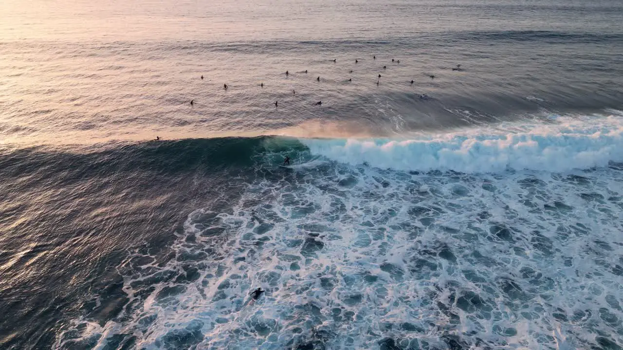 Aerial view of a surfer catching a wave at sunset