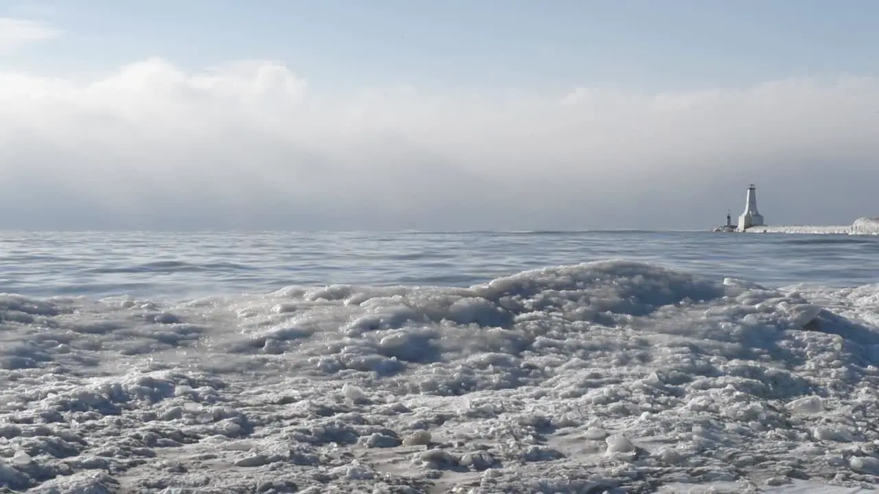 Ice and Snow Covered Beach with Lighthouse in the Distance