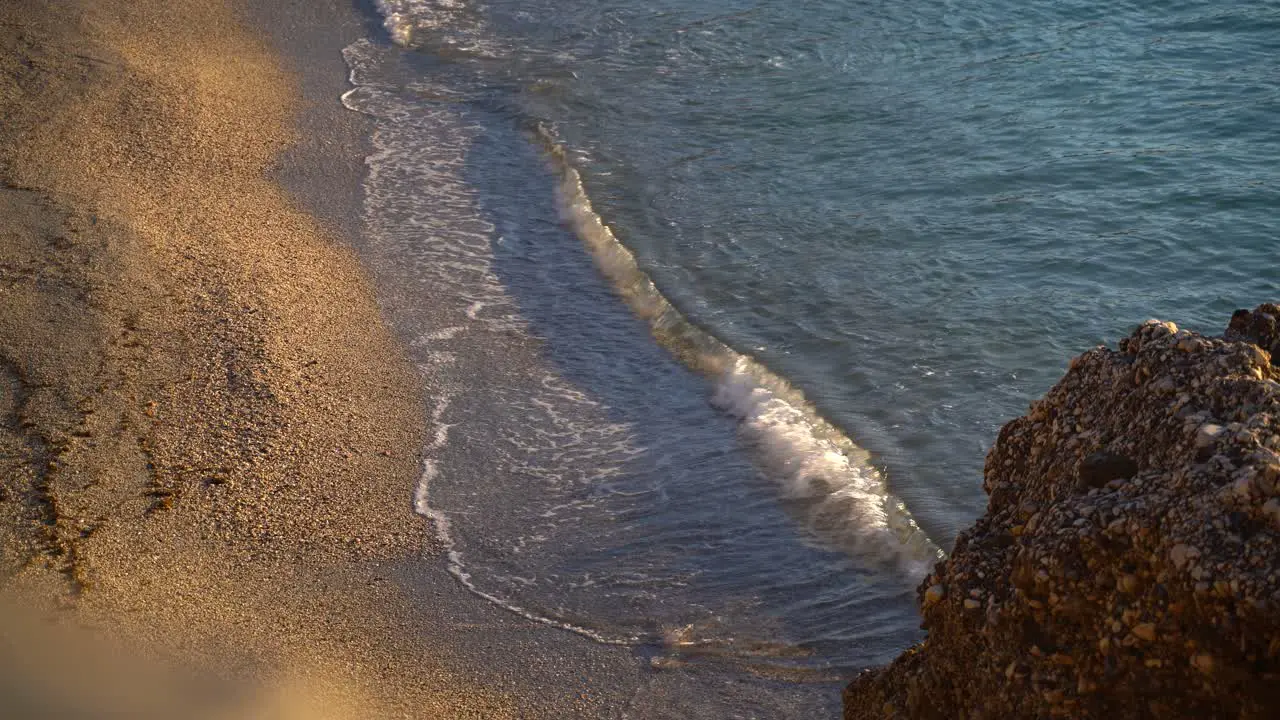 Looking down on golden sand on beach with calm waves breaking