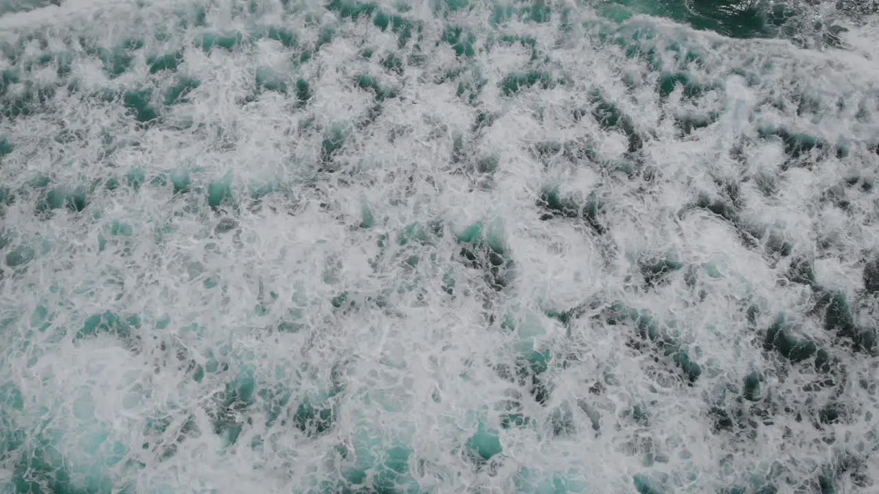 Aerial top view of waves crashing on rocks with the water making beautiful patterns and colours