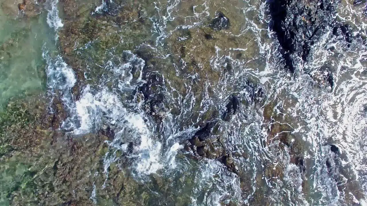 Overhead straight down aerial shot of water rushing in and out of reef