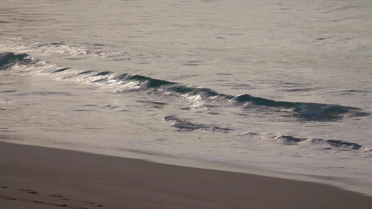 Manly Beach Sydney Australia waves crash in slow motion upon the sand in the early morning with the sunrising in the reflection