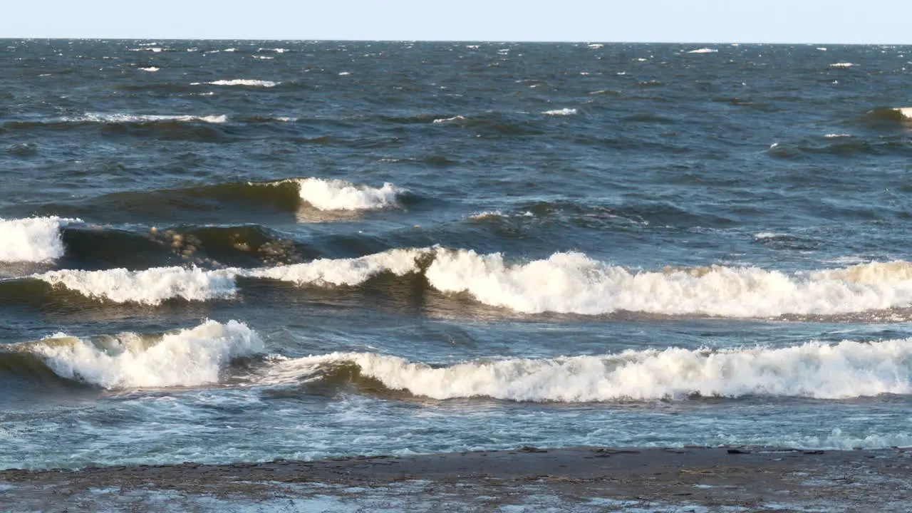 Rough ocean waves hitting sandy beach in cold and icy season slow motion