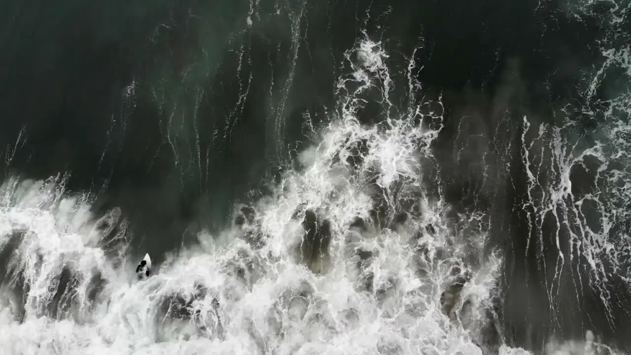 Crashing waves in ocean with surfer paddling out to surf in the PNW