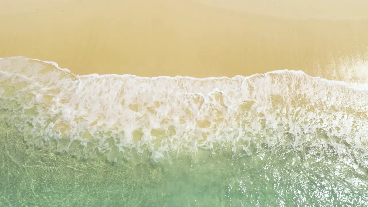 Aerial view of calming waves on beautiful sandy beach at tropical island in Indonesia