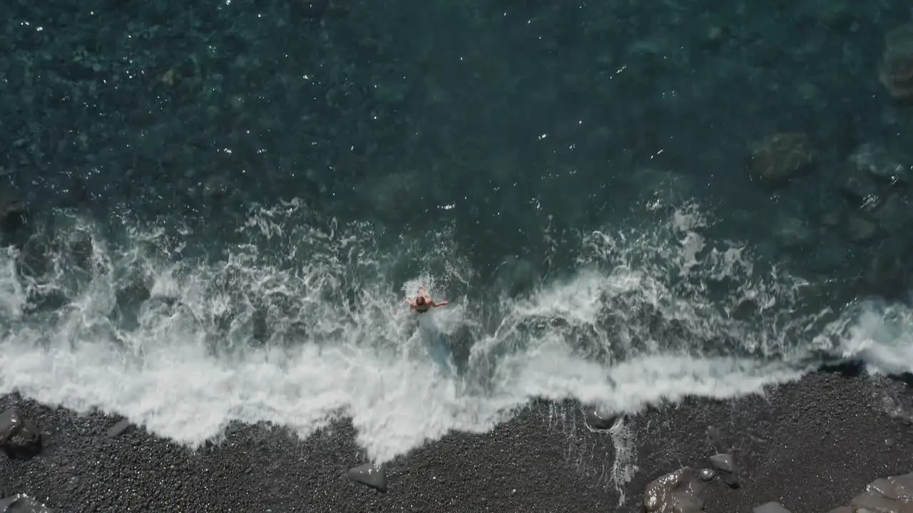 Top down of woman walking into clear ocean water for swimming at Madeira shore summer vacation