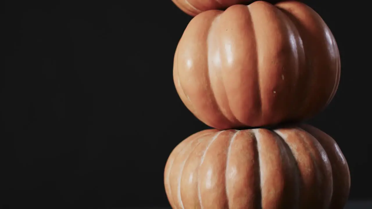 Video of stack of pumpkins on black background