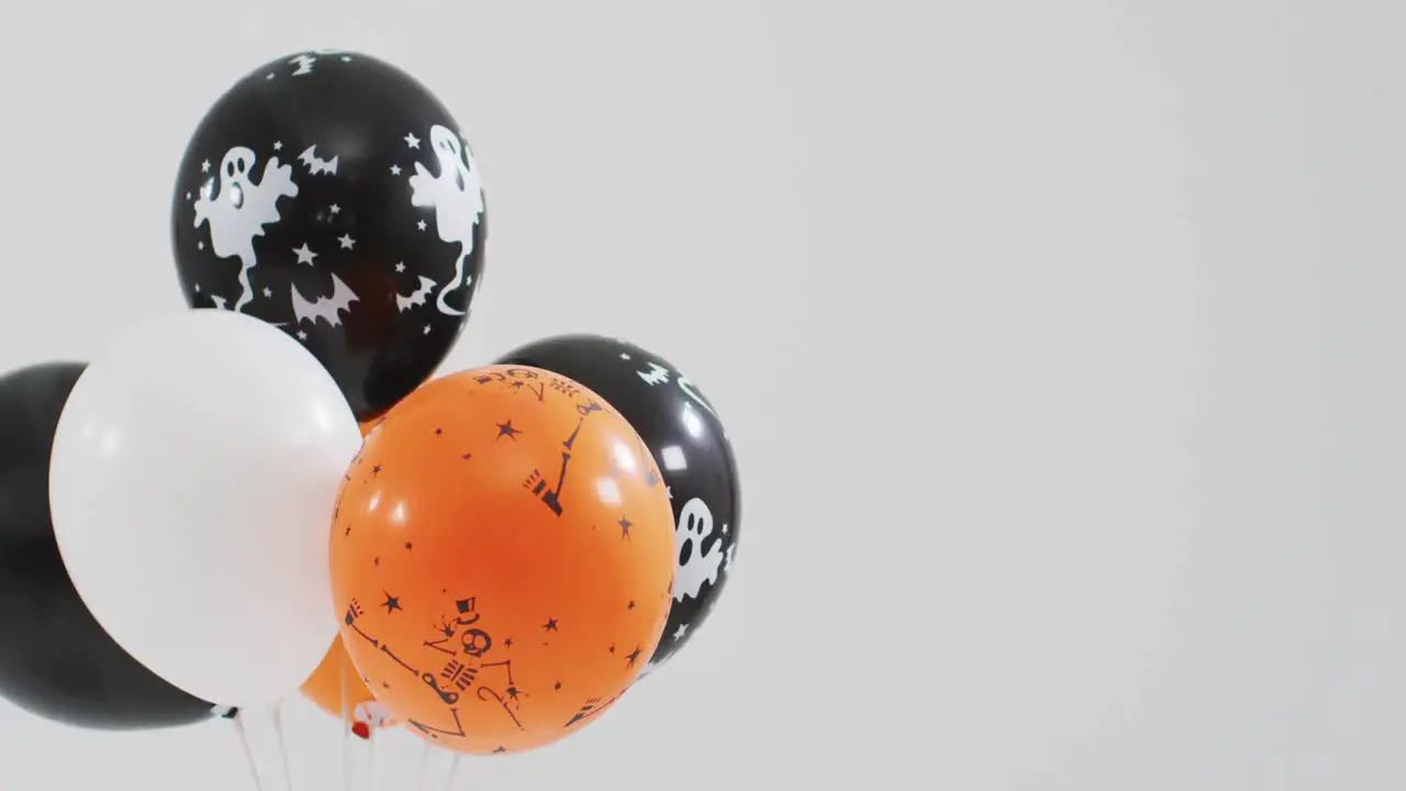 Ghost and skeleton printed bunch of halloween balloons against grey background