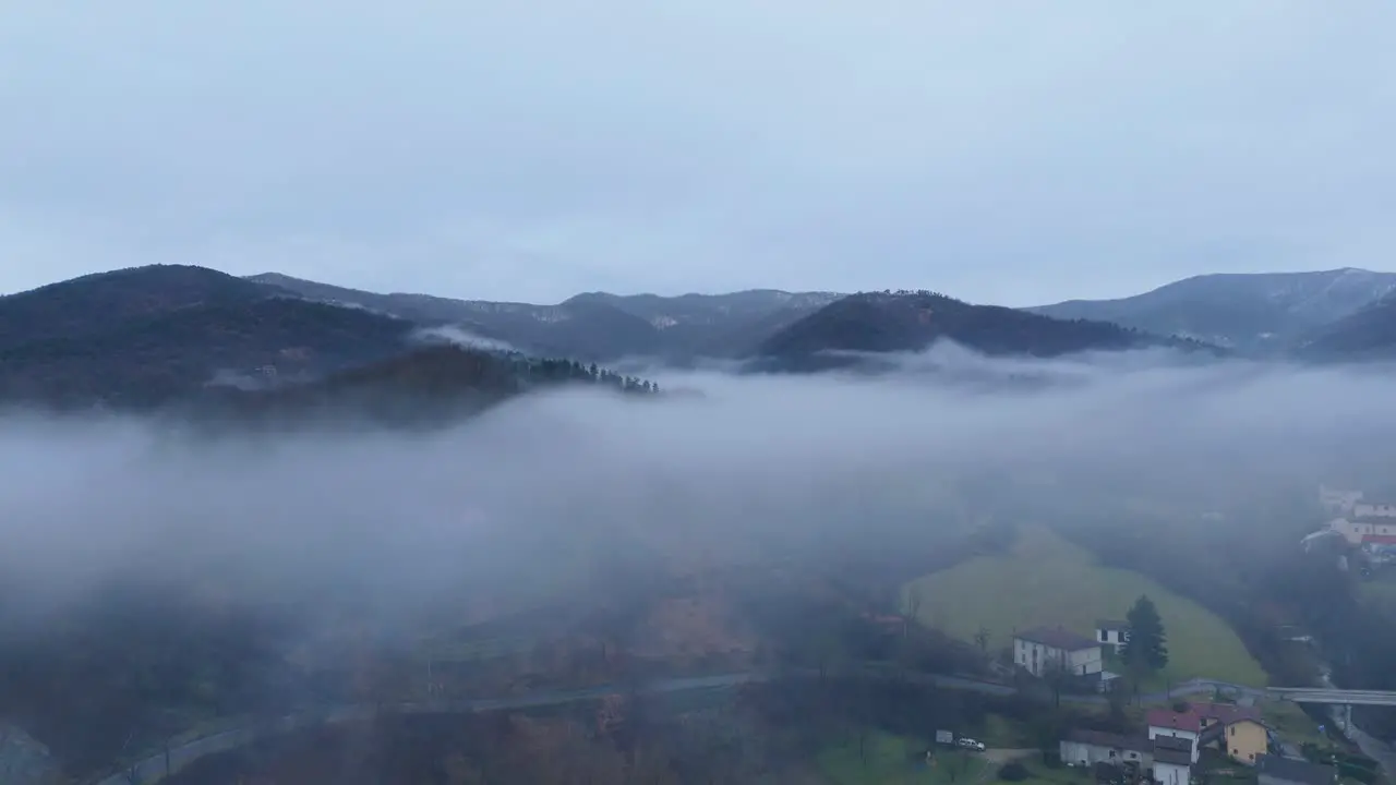 Overcast bleak sky and mist cloud over hilly countryside landscape