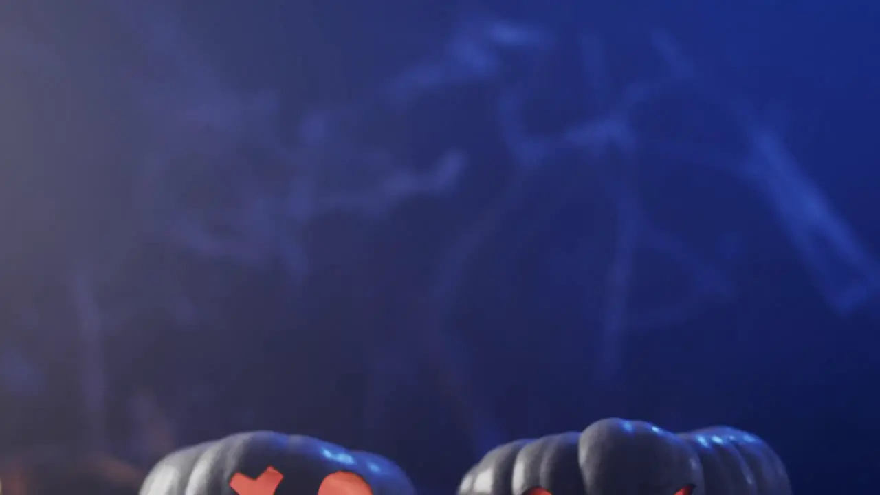 Video of halloween carved pumpkins and smoke with copy space on blue background