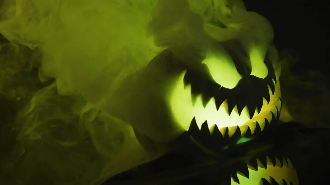 Video of halloween carved pumpkin with smoke and green light on black background