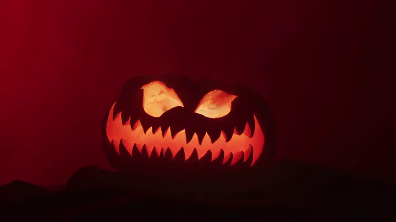 Video of halloween carved pumpkin with smoke and red light on black background