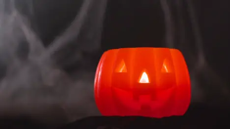 Halloween Pumpkin Jack-O-Lantern With Candle Against Black Background With Cobwebs With Smoke