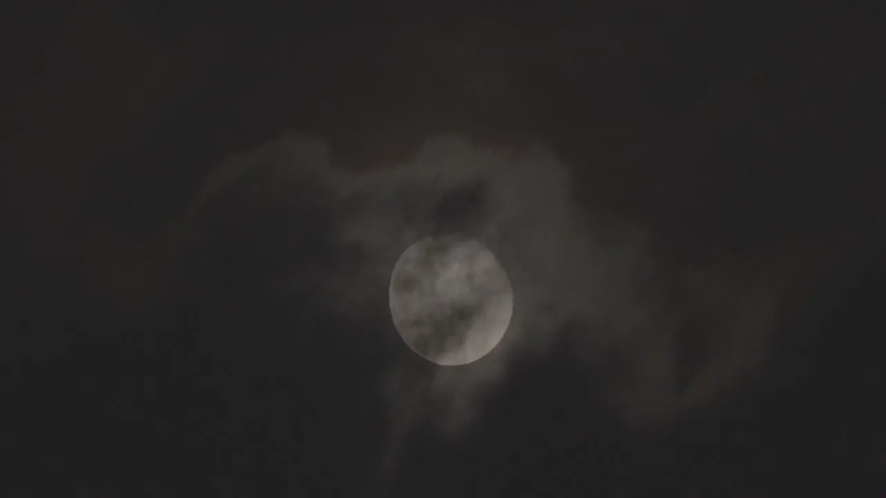 A full moon in a sky with clouds moving