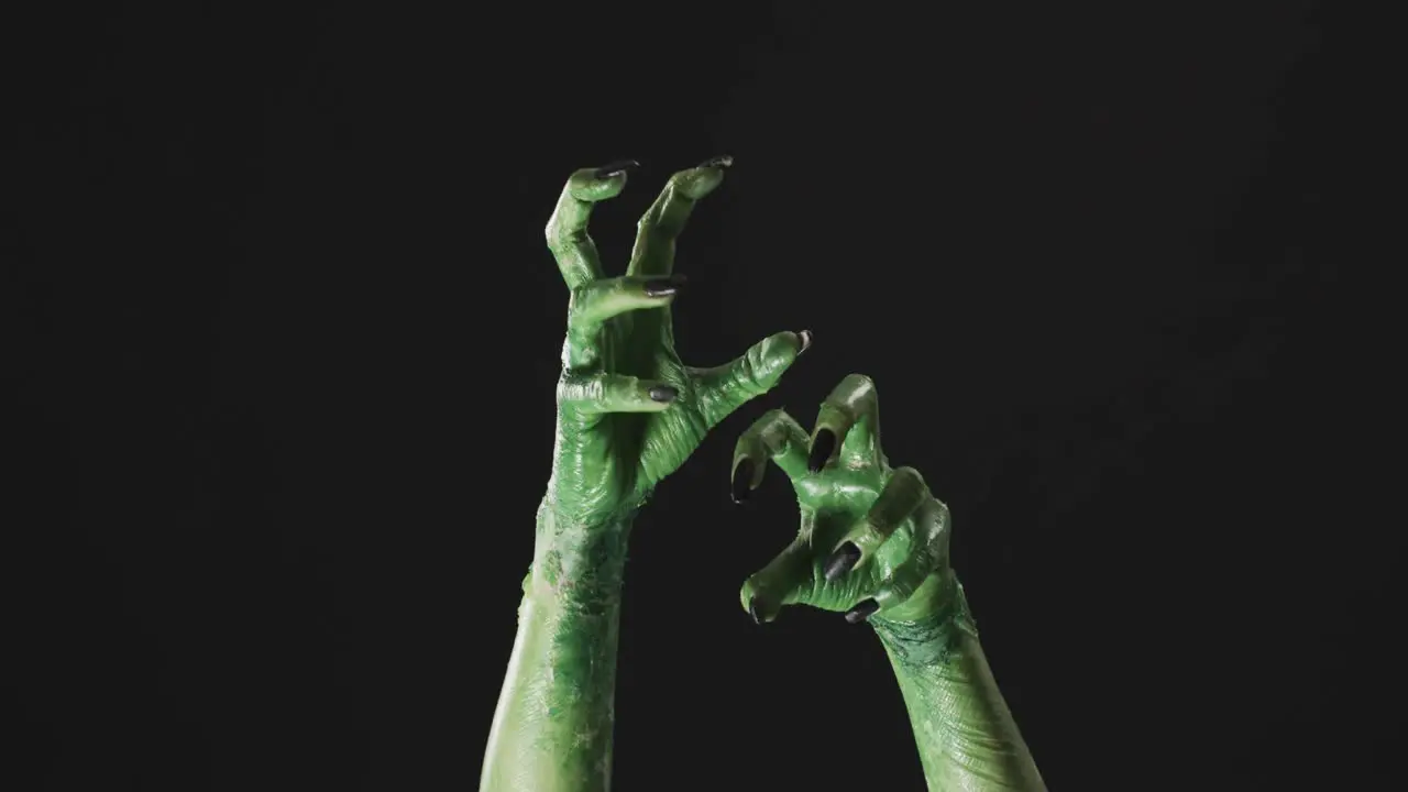 Video of halloween green monster hands with copy space on black background