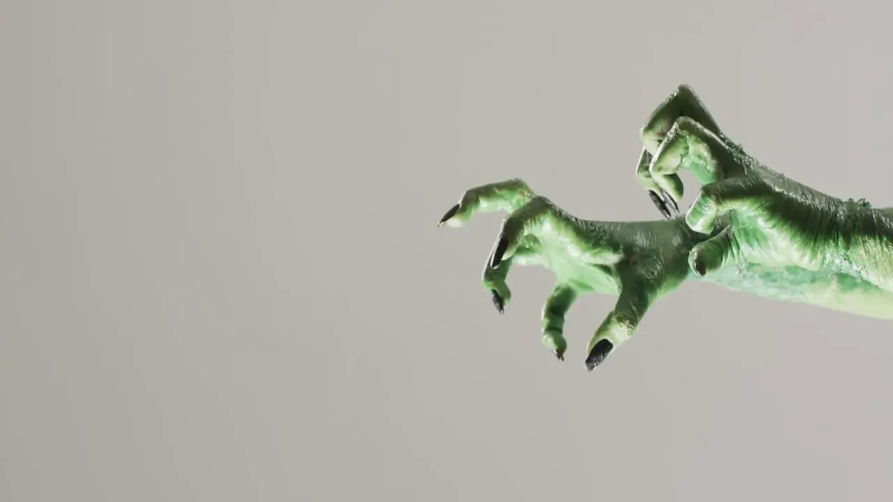 Video of halloween green monster hands with copy space on grey background