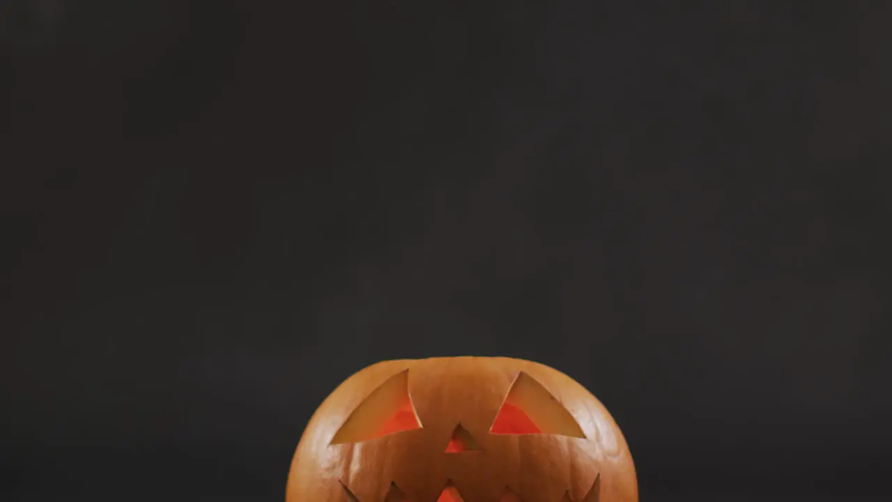 Smoke effect over scary face carved halloween pumpkin against grey background