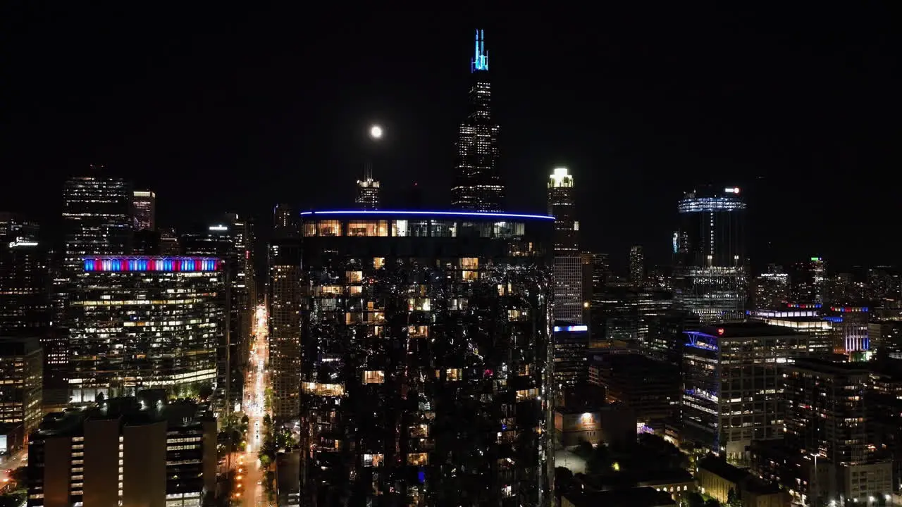 Static drone shot close to illuminated skyscraper windows in moon lit Chicago USA