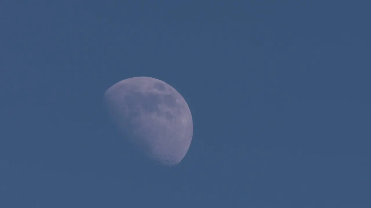 Half moon moving slowly across a blue sky