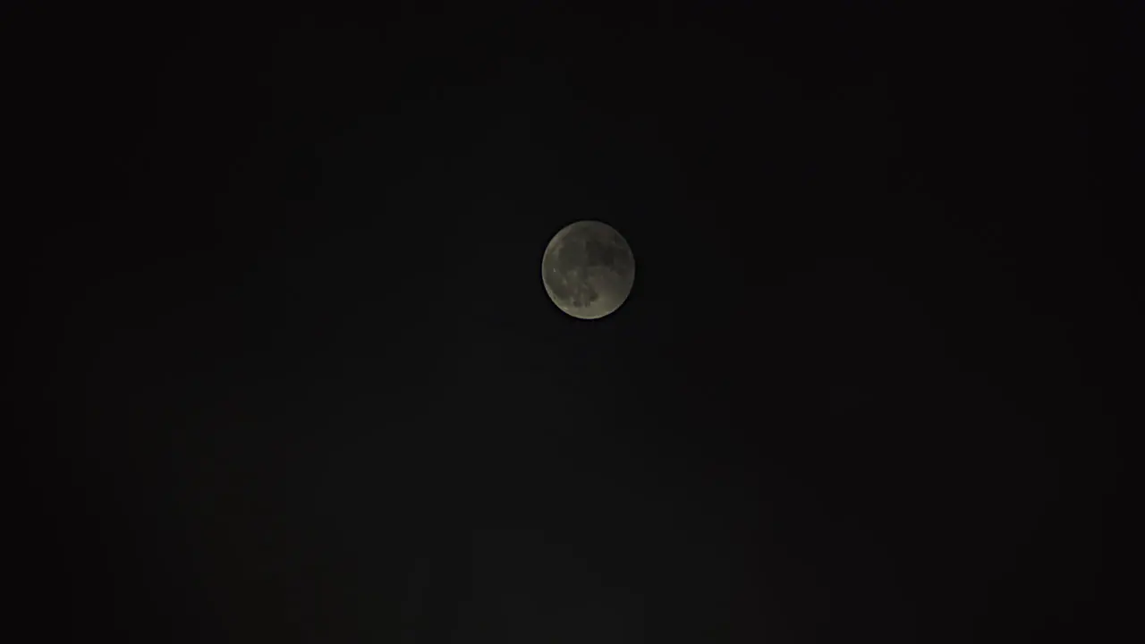 Wide shot of full moon as it is slowly covered with passing fog