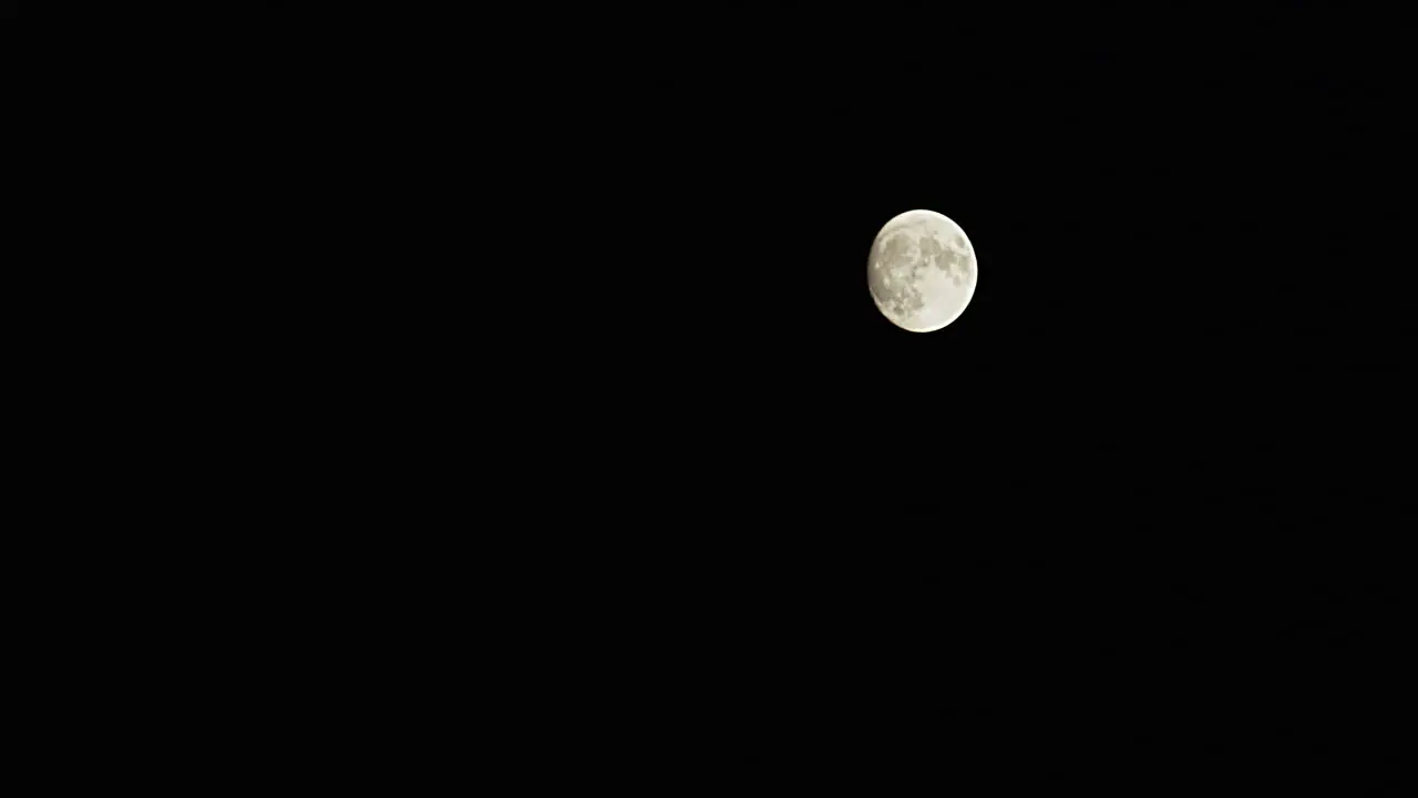 Time-lapse wide shot of a full moon as it rapidly rises from the lower left to the upper right