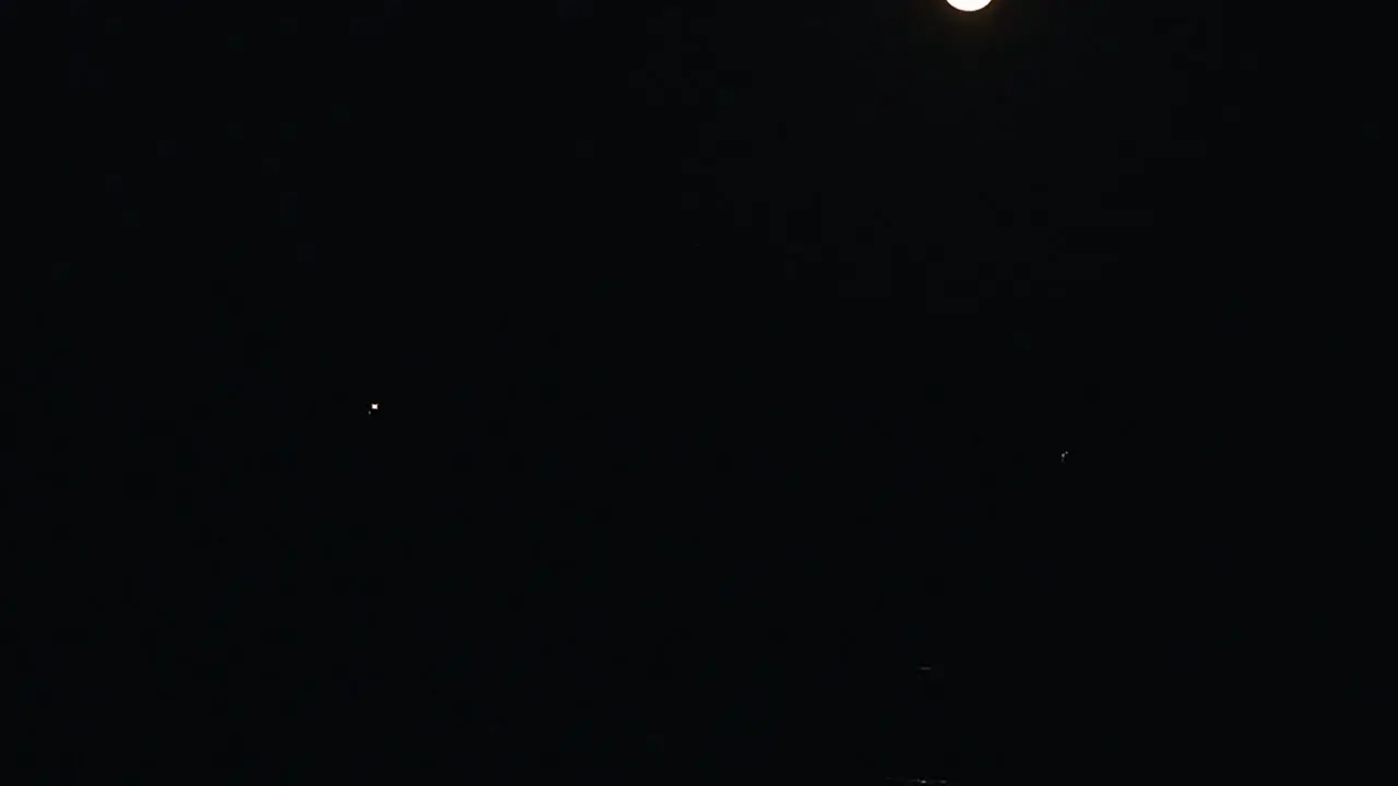 Time Lapse of the full moon rising in the night sky while reflecting in the water