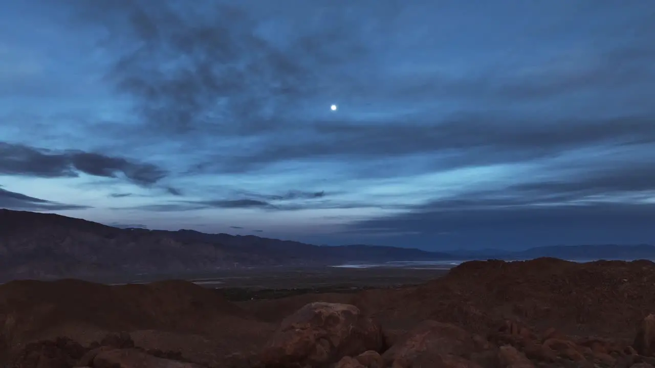 Famous and iconic rocks of Alabama Hills with a full moon starting to light up during blue hour