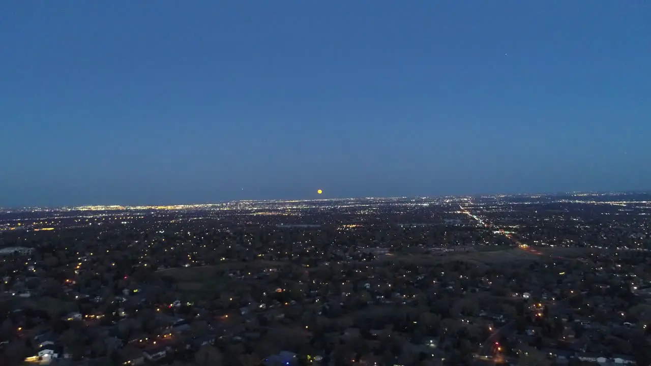 A drone flight at civil twilight capturing a Halloween Moon Rising over Denver CO