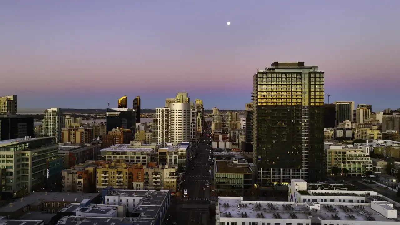 Aerial view of sunlit streets of San Diego colorful sunset during full moon in full moon Ascending drone shot