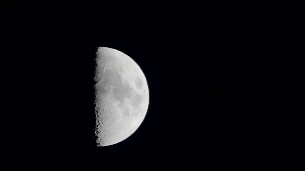 A shot of a first quarter moon slowly rising from up in the sky in Tokyo Japan