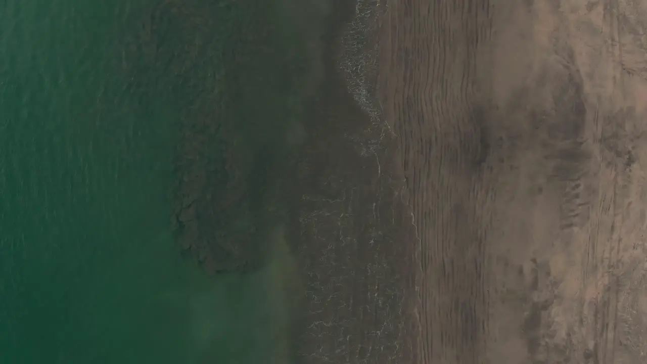 Aerial birds eye view of green waves washing up on Costa Rica beach