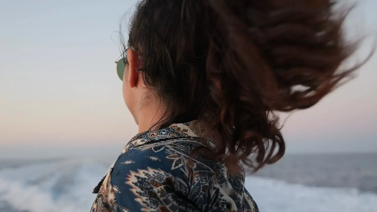 A woman enjoys the wind in her hair while on a boat ride close-up slow motion