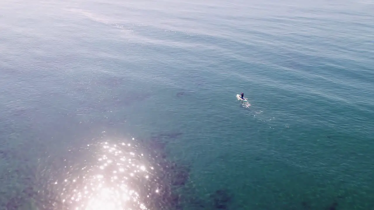 Drone flying on the Mediterranean sea birds eye view over a paddleboarder rotating into the horizon