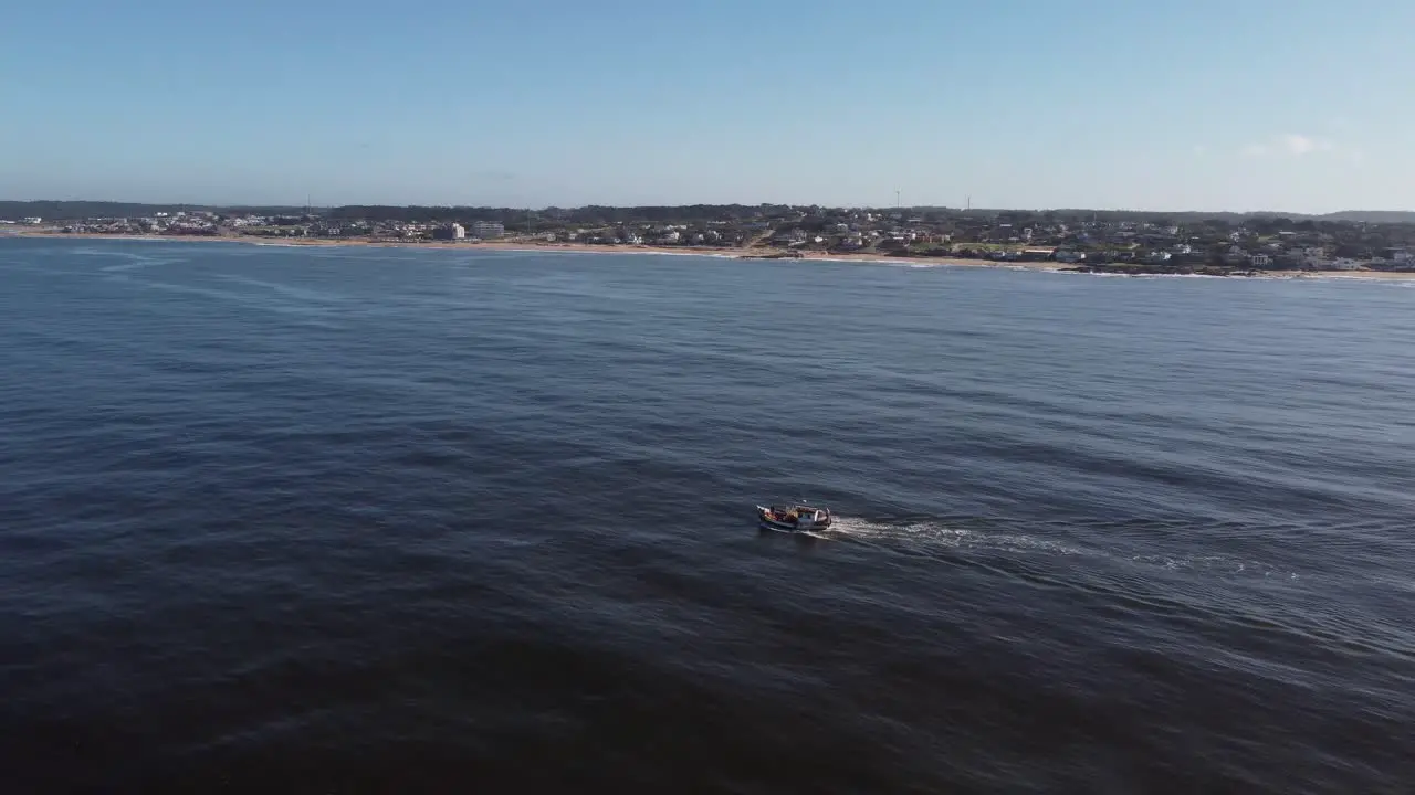 Fishing boat navigating on Atlantic ocean with Uruguayan coastline in background