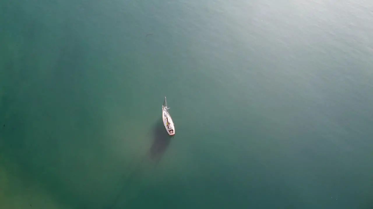 Sail Boat anchored in bay with pier in background