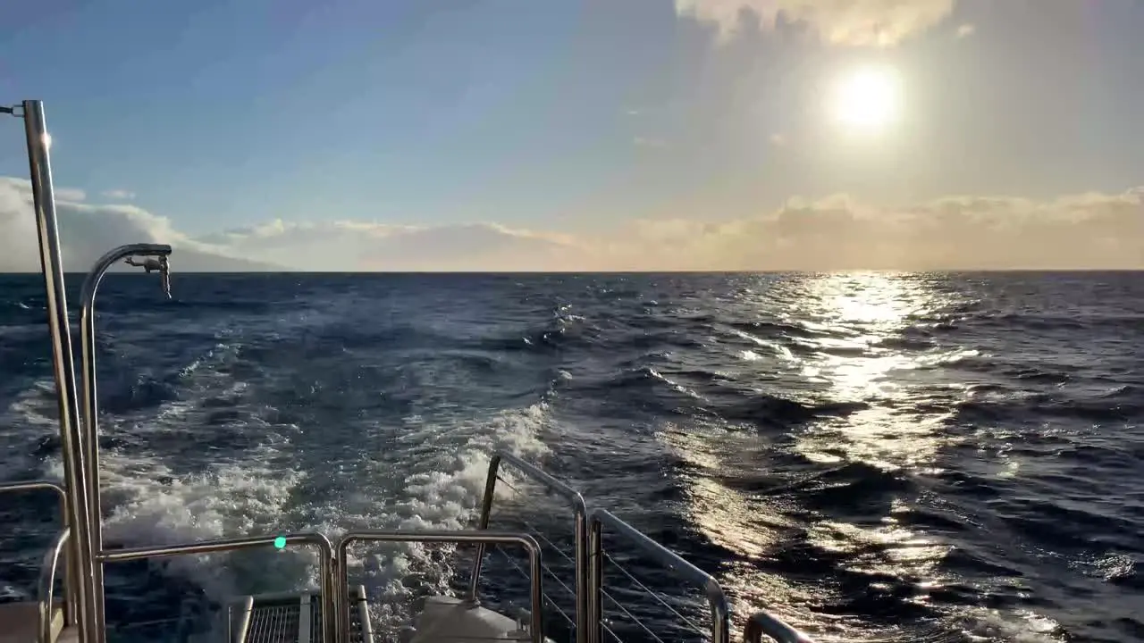 Back of a Catamaran looking out at sun over ocean