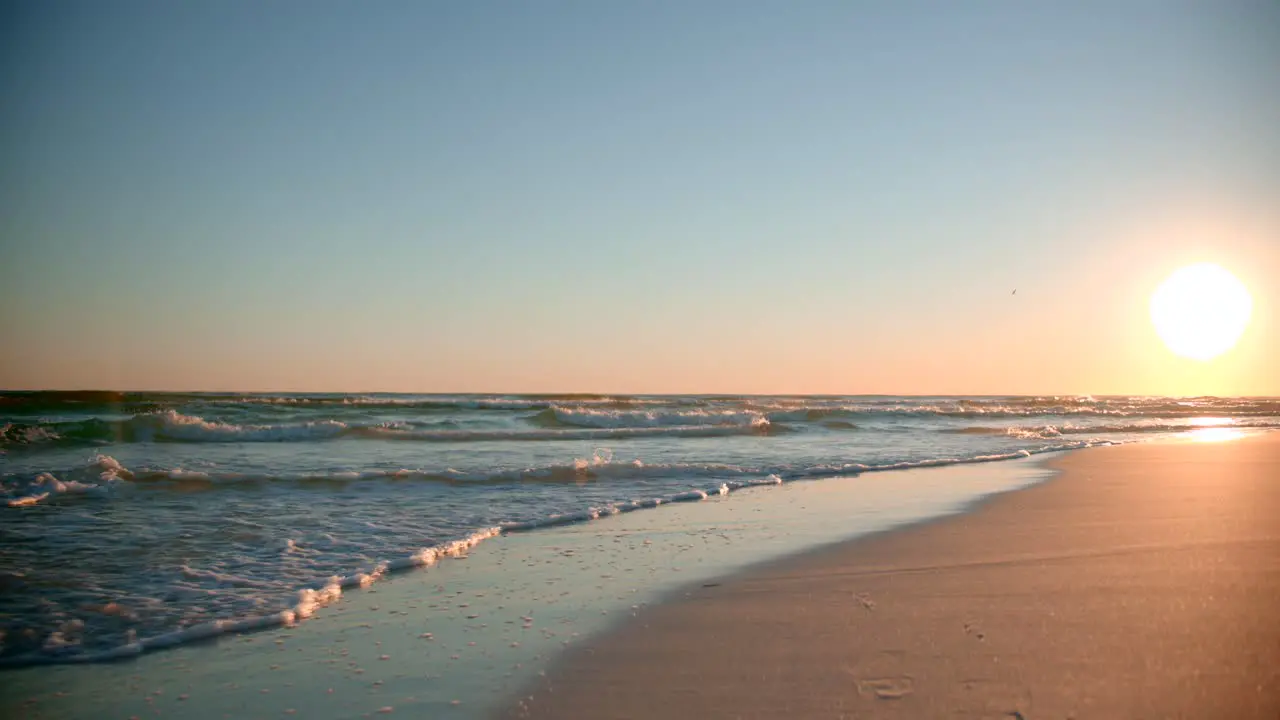 Shots of the ocean on a warm sunny evening with footprints in the sand facing the sun directly