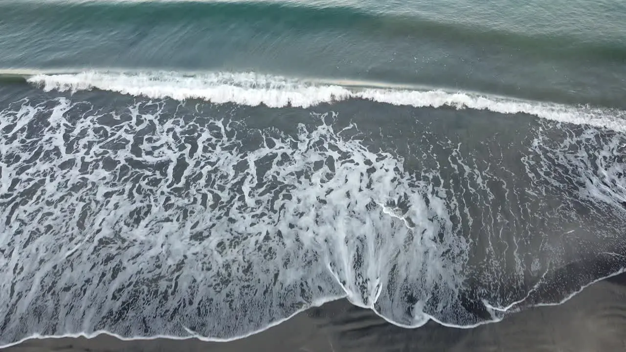 Drone shot of waves in the seashore with woman walking