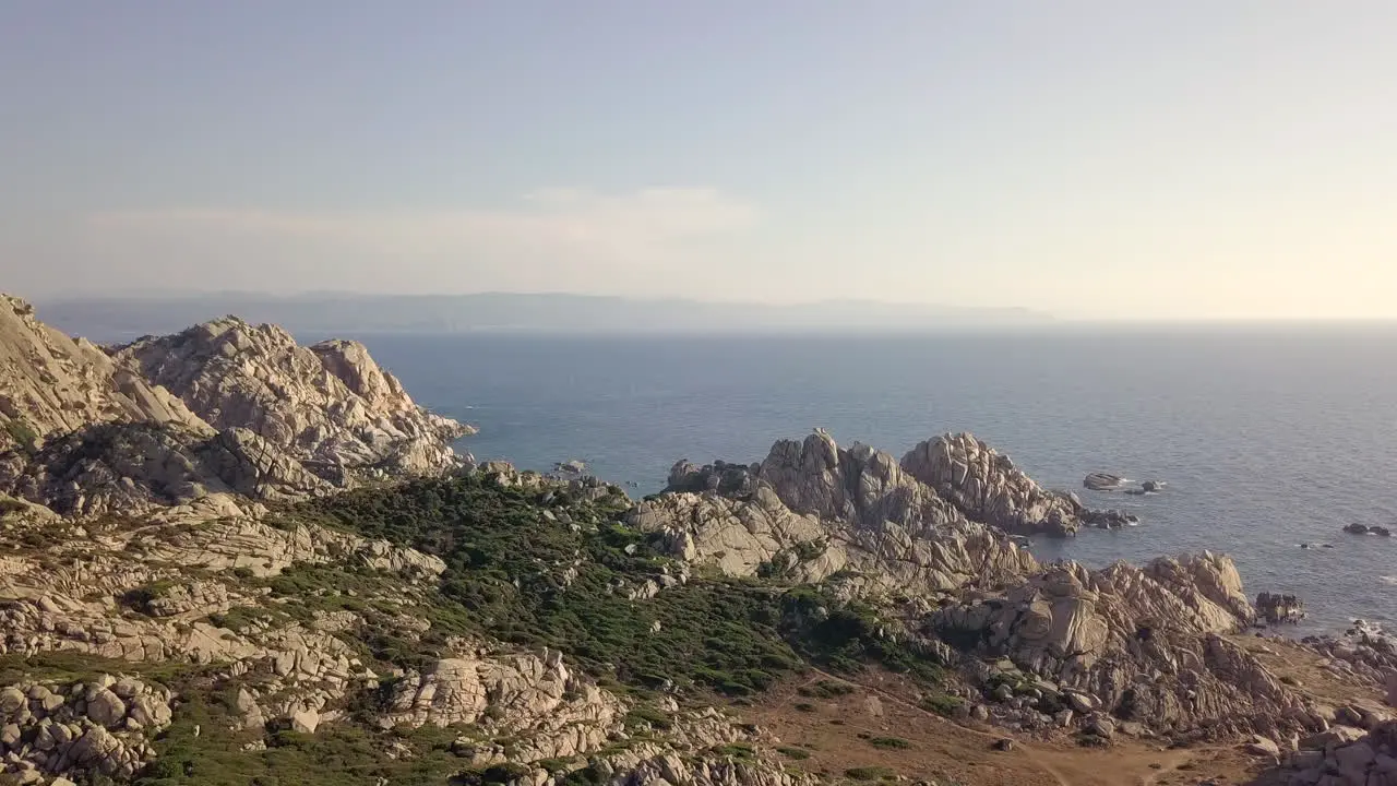 Drone shot flying over a rocky cliff towards the ocean