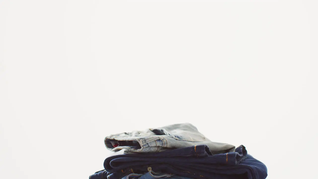 Close up of folded jeans with different shades on white background with copy space