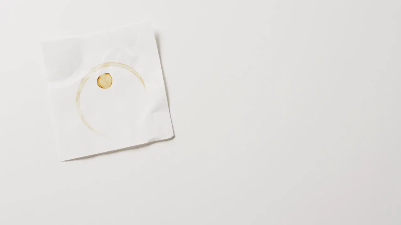 Video of close up of piece of paper with coffee mug ring stain on white background with copy space