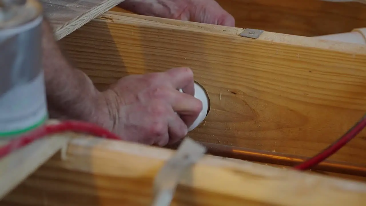 Plumber fitting plumbing through floor joist