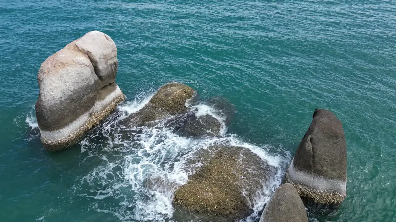 Few rocks and stones raised above the sea level in middle of the sea being hit by rough waves